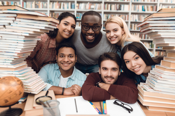 a group of diverse students posing in a library filled with books